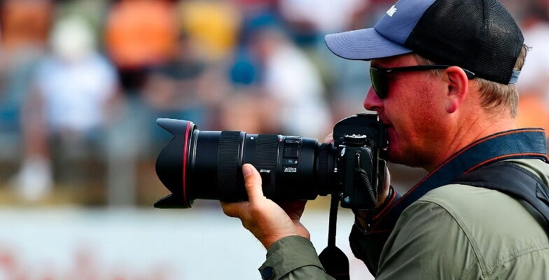 چگونه یک عکاس ورزشی حرفهای شویم | آموزش کامل عکاسی ورزشی از مبتدی تا حرفهای 1 عکاس ورزشی در کنار زمین فوتبال در حال تمرکز بر جریان بازی برای پیشبینی لحظه حساس گل.