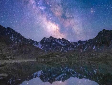 تصویری خیره‌کننده از کهکشان راه شیری بر فراز یک منظره کوهستانی در شب