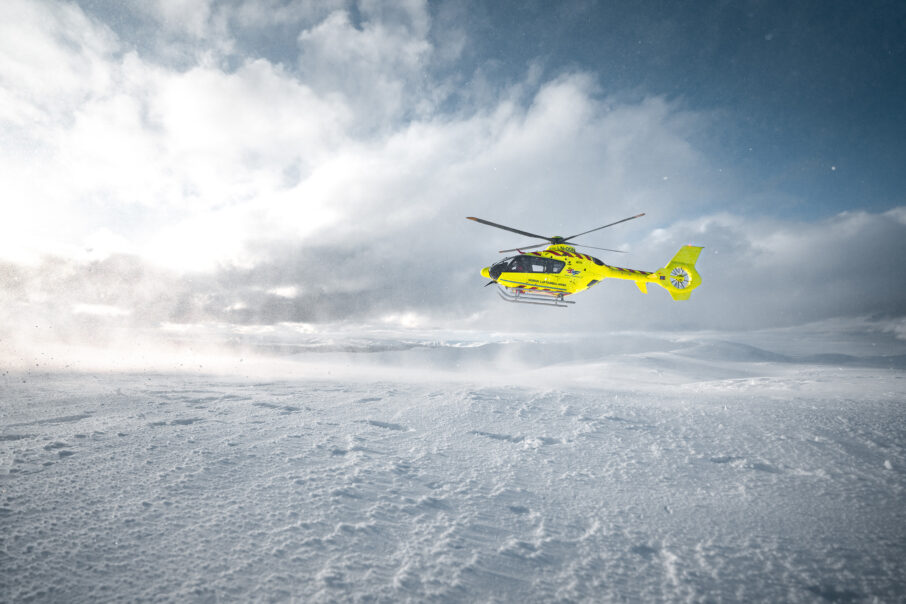 هلی‌کوپتری با رنگ زرد که در بالای یک منظره برفی قرار دارد.