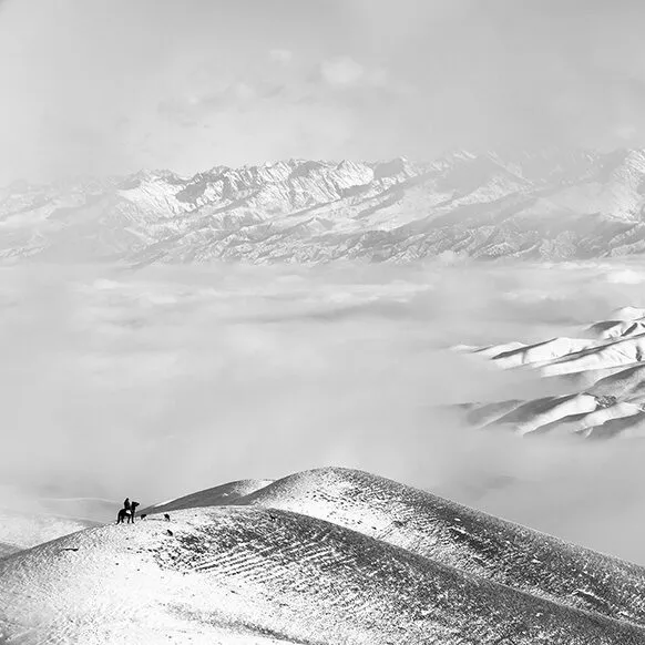 سوارکار تنها بر فراز کوه نشسته و به یک چشم‌انداز برفی دور نگاه می‌کند.