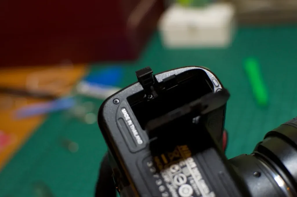  دستی که در حال خارج کردن باتری از یک دوربین نیکون خیس است 