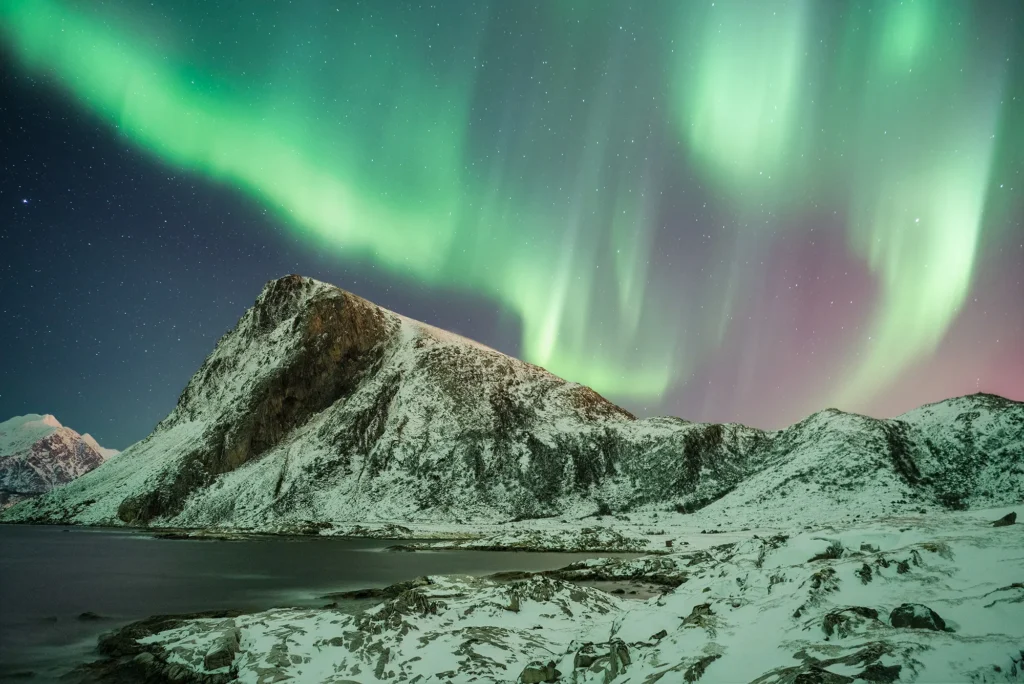هنر عکاسی منظره استثنایی: فلسفه و تکنیکهای مایکل شاکه 4 این ترجمه به توصیف تصویری از شفق قطبی و زیبایی طبیعی آن در پسزمینه کوههای پوشیده از برف اشاره دارد.