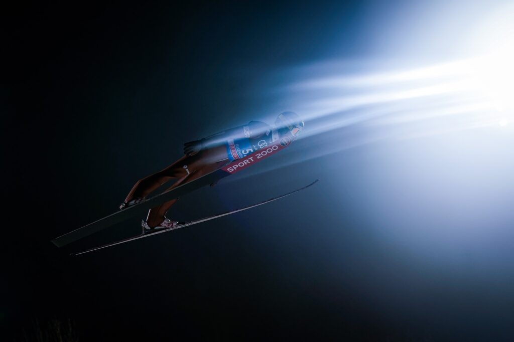 عکس نشان‌دهنده یک پرش‌اسکی در برابر آسمان تاریک است.