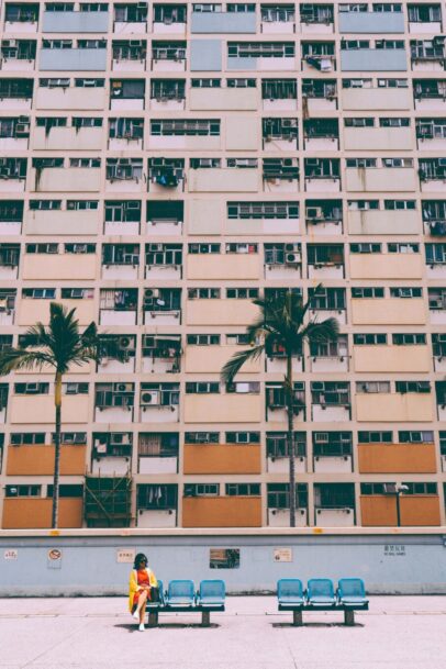 یک عکاس با دوربین روی شانه در حال قدم زدن در یک خیابان شلوغ و نگاه کردن به اطراف با کنجکاوی. 