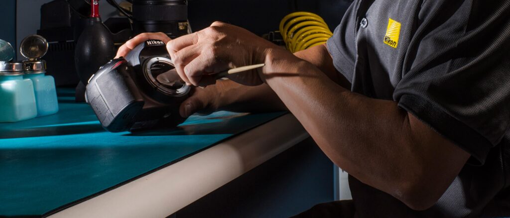 فرآیند تمیزکاری سنسور یک دوربین نیکون با استفاده از سواب و مواد مخصوص در یک محیط ایزوله